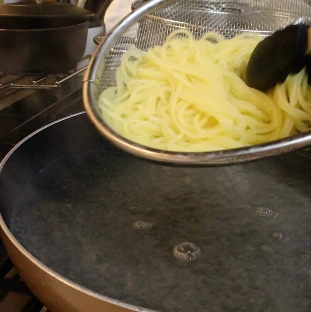 茹で上がったパスタをザルで湯切りしているところ